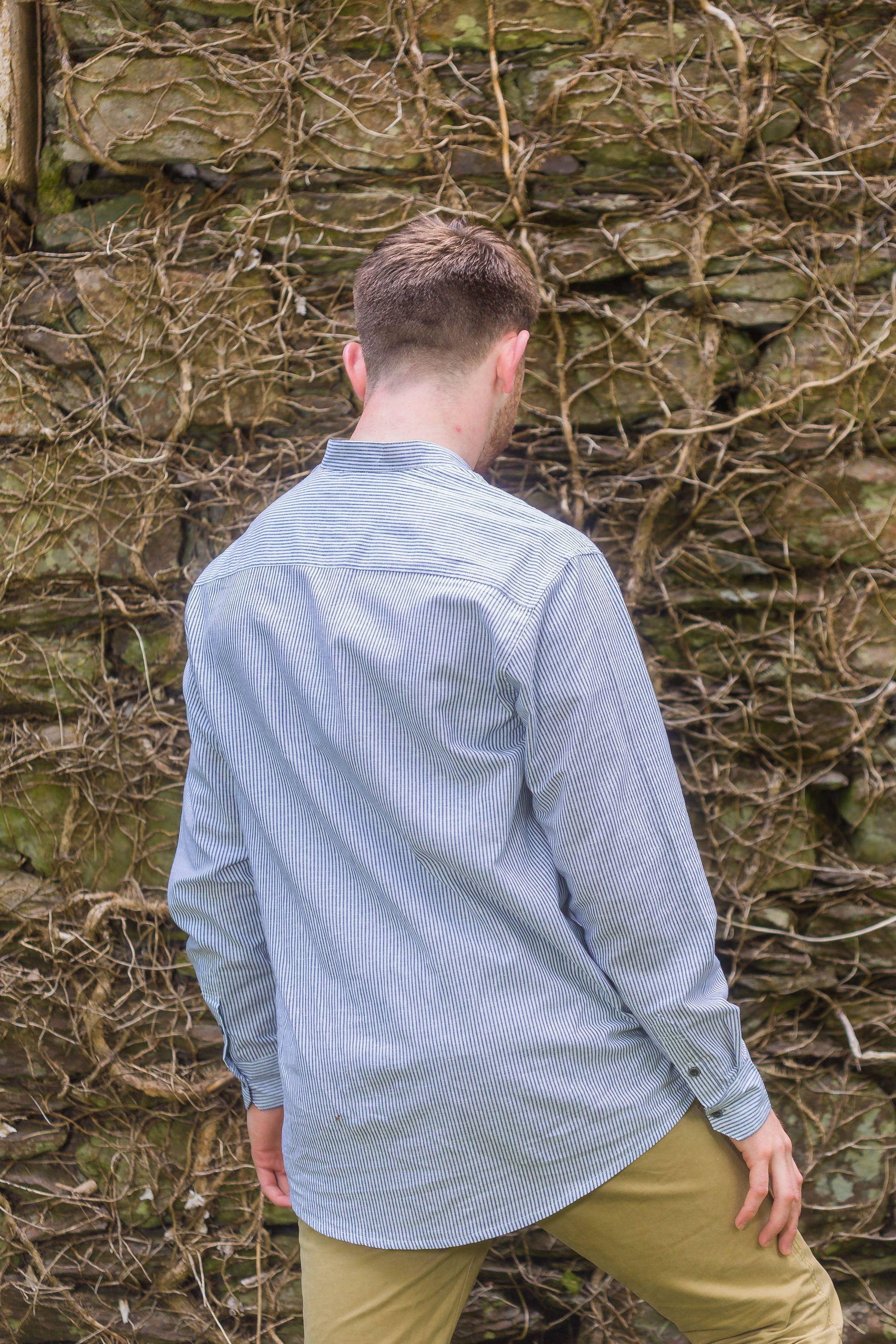 Blue and white striped linen shirt with a stand collar, sold in London, Ontario, shown on an Irish bloke in front of a wall. Shirt is for men or women.